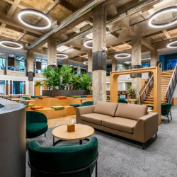 Cozy breakout zone with a tan leather sofa and green velvet armchairs.