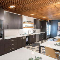 Modern kitchenette and breakroom with dark cabinets and cafe-style seating.
