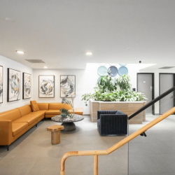 Reception lounge area with a large orange sofa and abstract wall art.