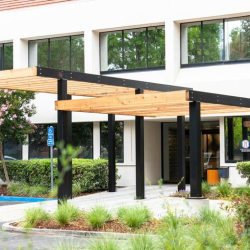 Exterior entrance of the office building with a modern wooden pergola.