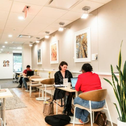 Long communal workspace with cafe-style tables and people working.