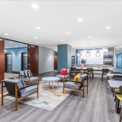Modern lounge area with colorful chairs and a bright kitchen in the background.