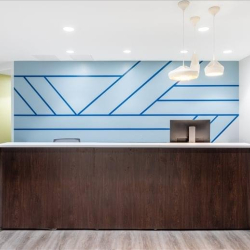 Sleek reception desk with a blue geometric feature wall and pendant lighting.