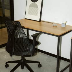Sleek workstation with a black mesh chair and abstract wall art.