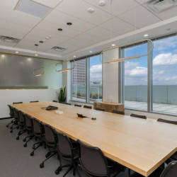 Professional boardroom with a long wooden table and city panoramas.