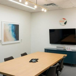 Compact meeting room with a wall-mounted TV and beach-themed art.