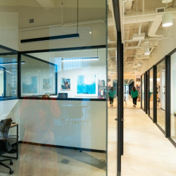 Clean office hallway featuring glass partitions and exposed ceilings.