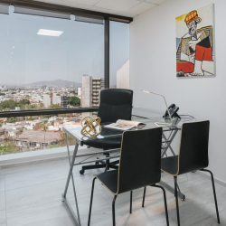 Private office featuring a glass desk and expansive city views through large windows.