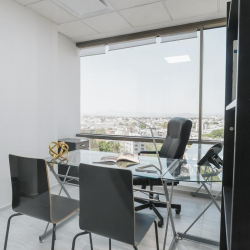 Minimalist private office with a glass desk and black ergonomic chair.