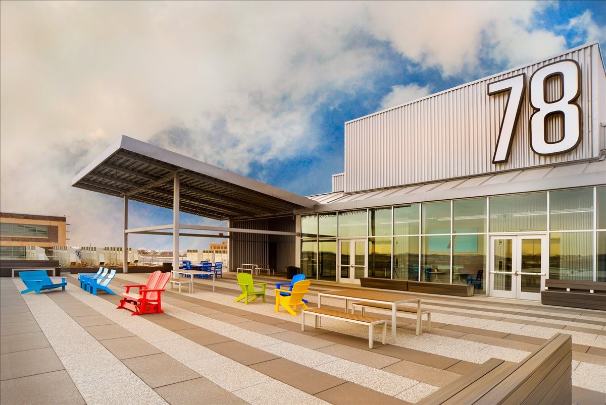 Modern exterior facade of 78 John Miller Way, Suite 102 with a spacious patio and colorful Adirondack chairs.