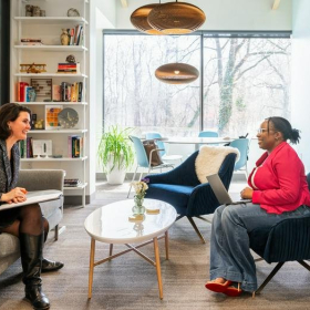 Two women collaborating in a modern, sunlit lounge at HAYVN.. Click for details.