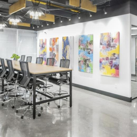 Large, high-topped meeting table with several stools and colorful abstract art on the wall.. Click for details.